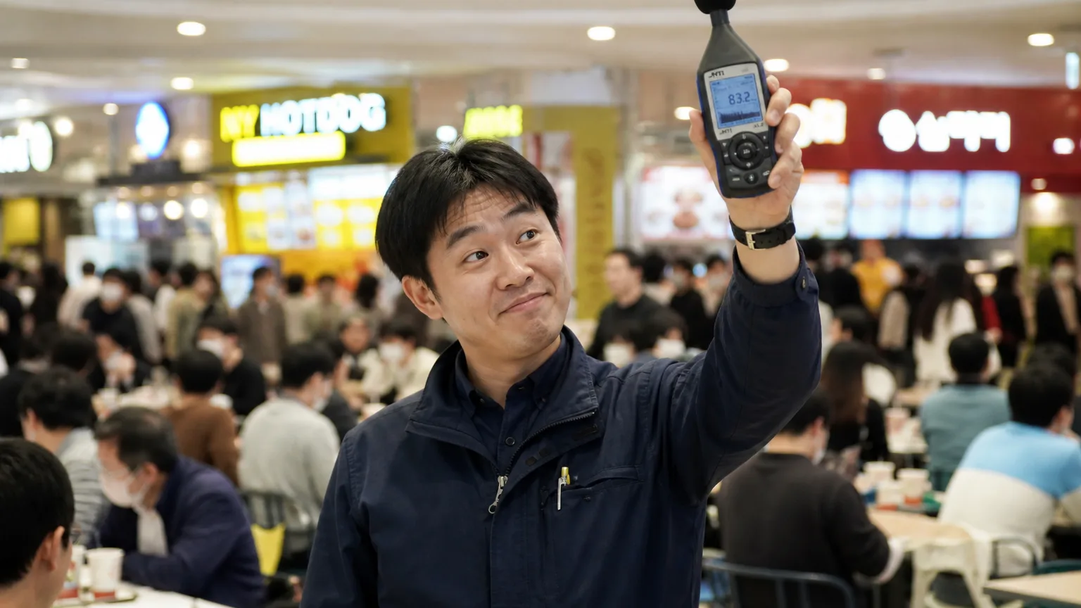 백화점 소음 기준을 체감하며 놀란 표정으로 소음계를 들어올린 엔지니어